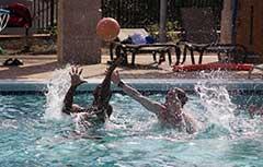 Two male students playing water 篮球 in Campus Rec outdoor pool.